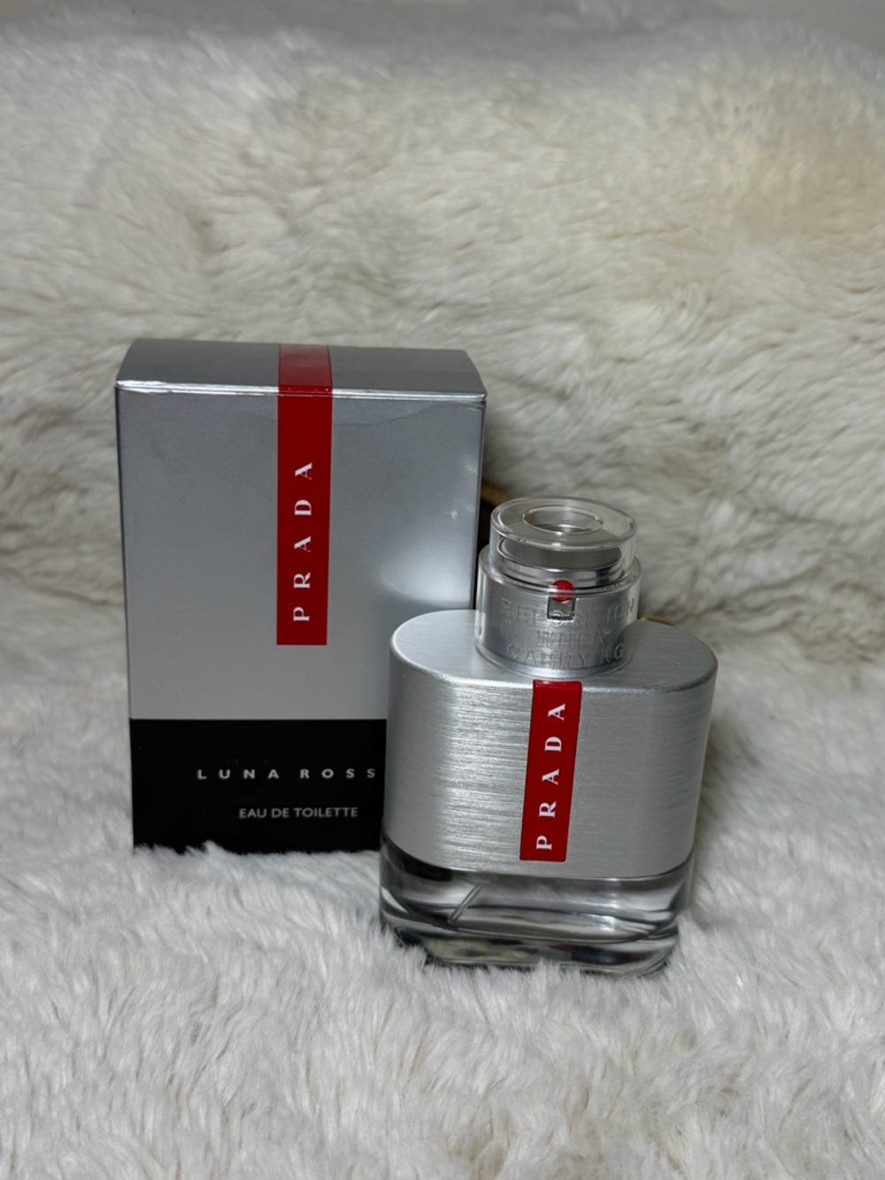 Prada silver bottle with black box and red accent